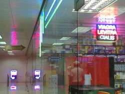 Una farmacia vende prodotti tipici locali ben pubblicizzati con insegne al neon.